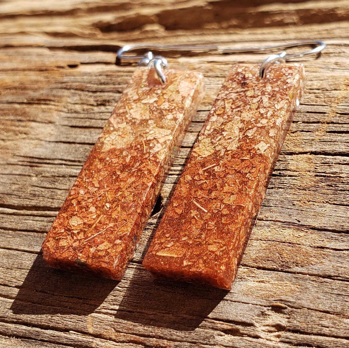 Rectangular natural brown dried leaf earrings on a wooden surface
