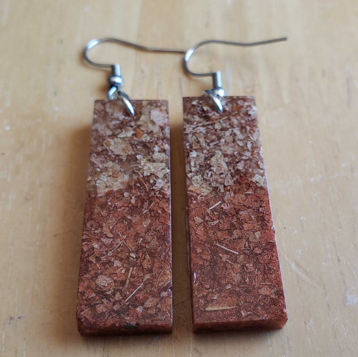 Rectangular brown dried leaf earrings on a wooden surface