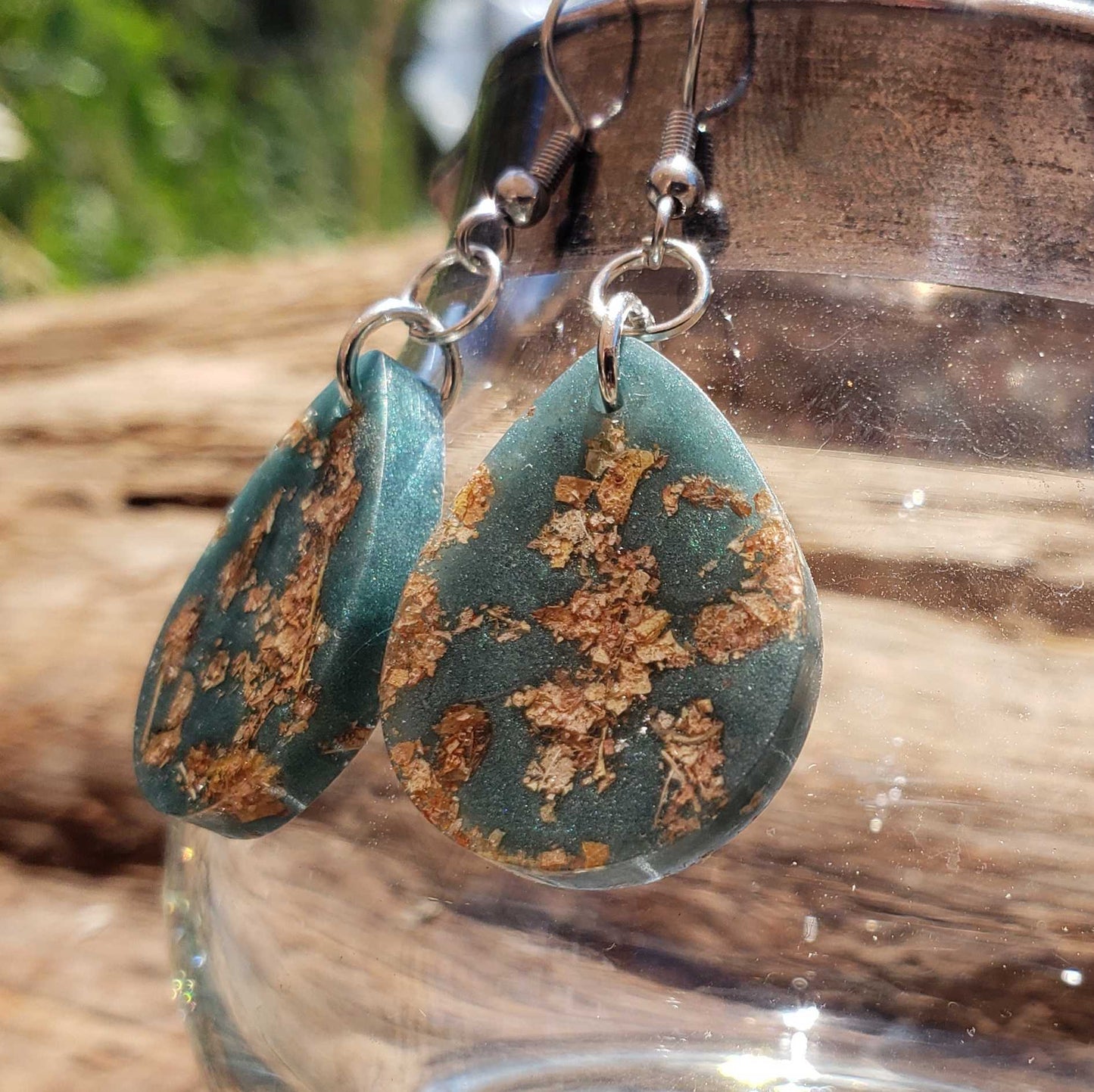 Teal earrings with gold leaf pattern made from dried leaves on a wooden surface
