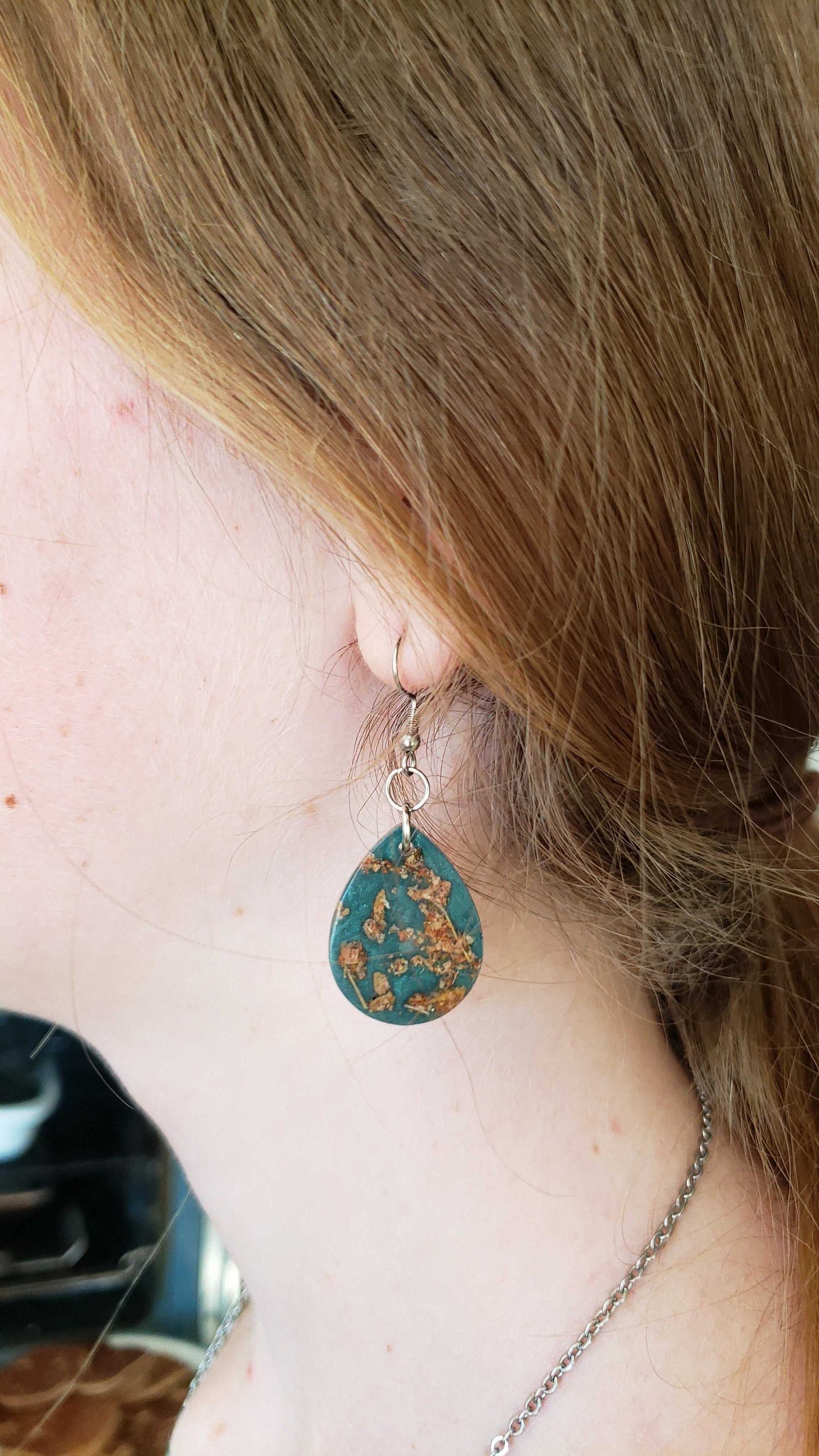 Turquoise teardrop earrings with gold pattern made from dried leaves.