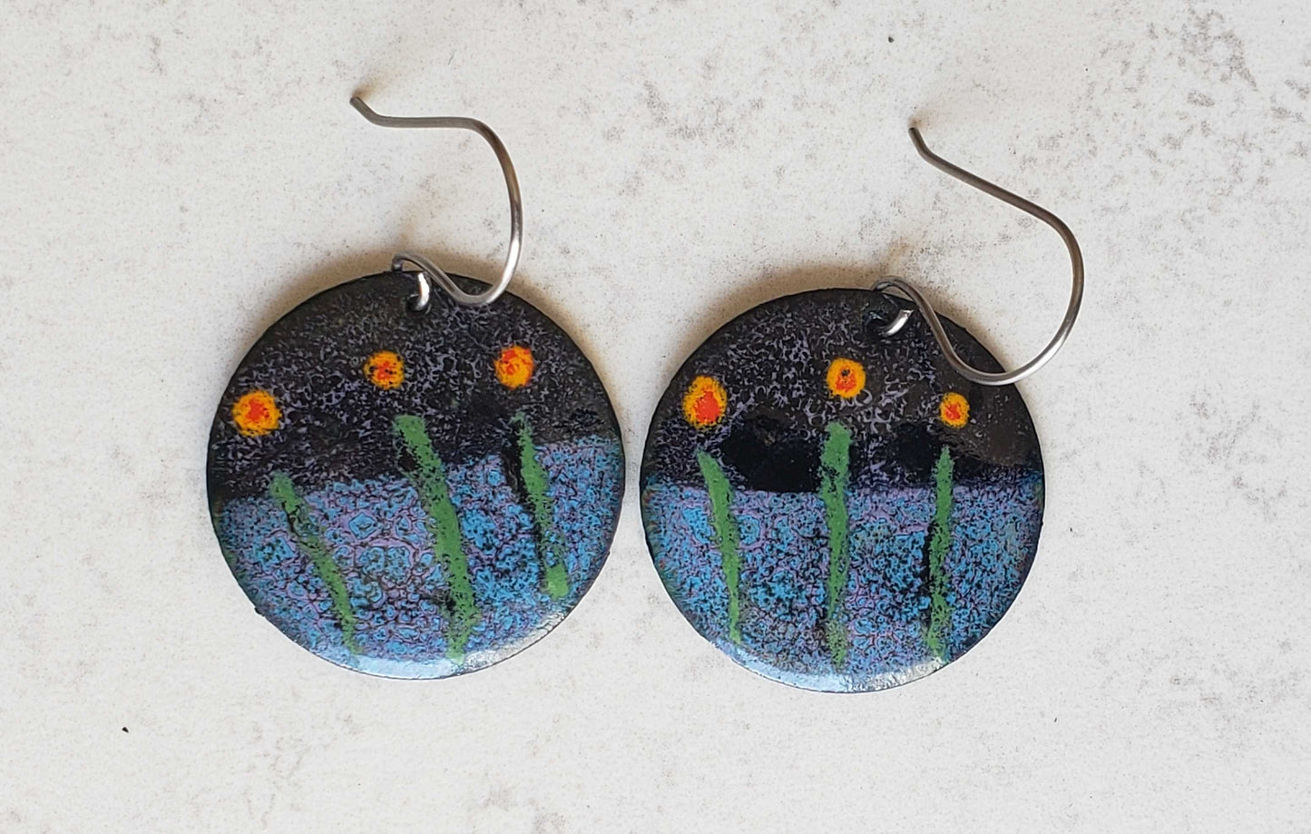 Round copper earrings with flower-themed design on a light gray background