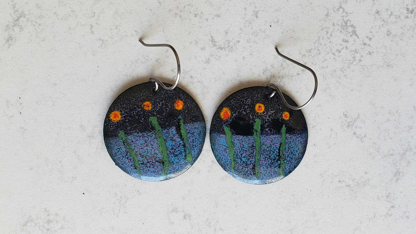 Pair of round copper earrings with floral design on a textured surface