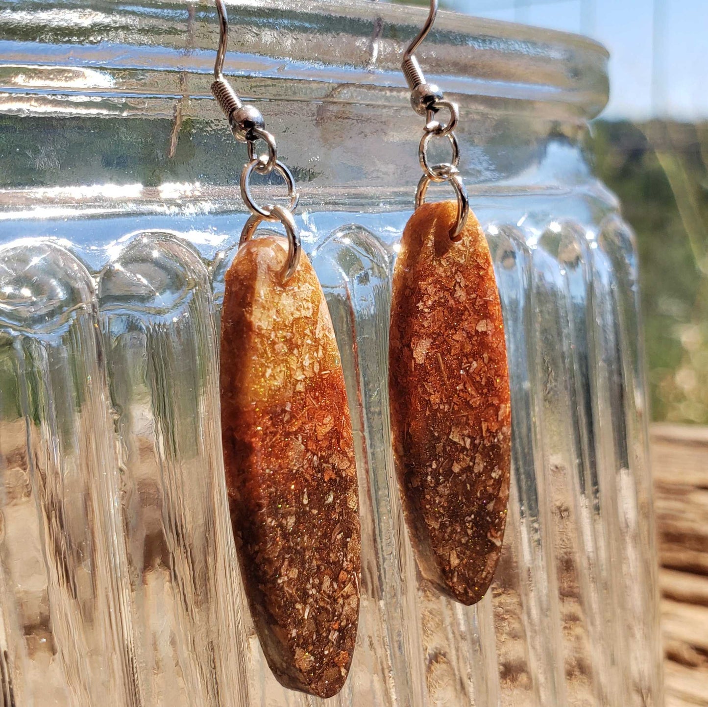 Boho brown oval earrings made from dried leaves hanging from a glass jar