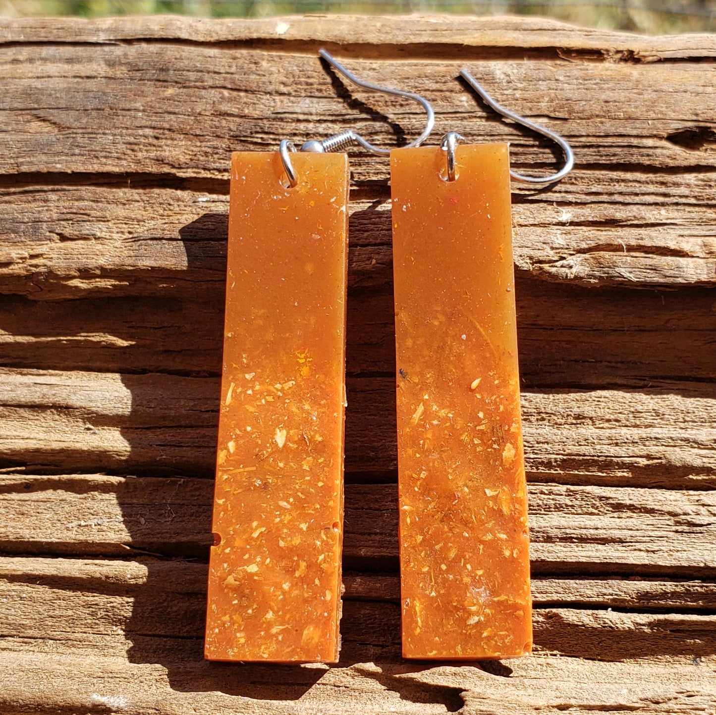 Pair of brownish amber bar-shaped boho earrings on a wooden surface