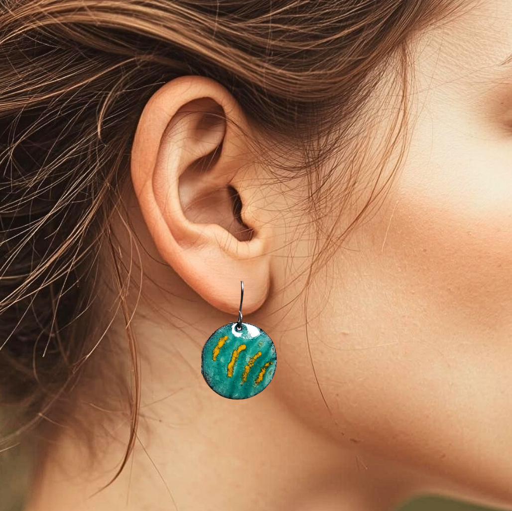 Close-up of an ear wearing a blue copper earring with yellow accents.