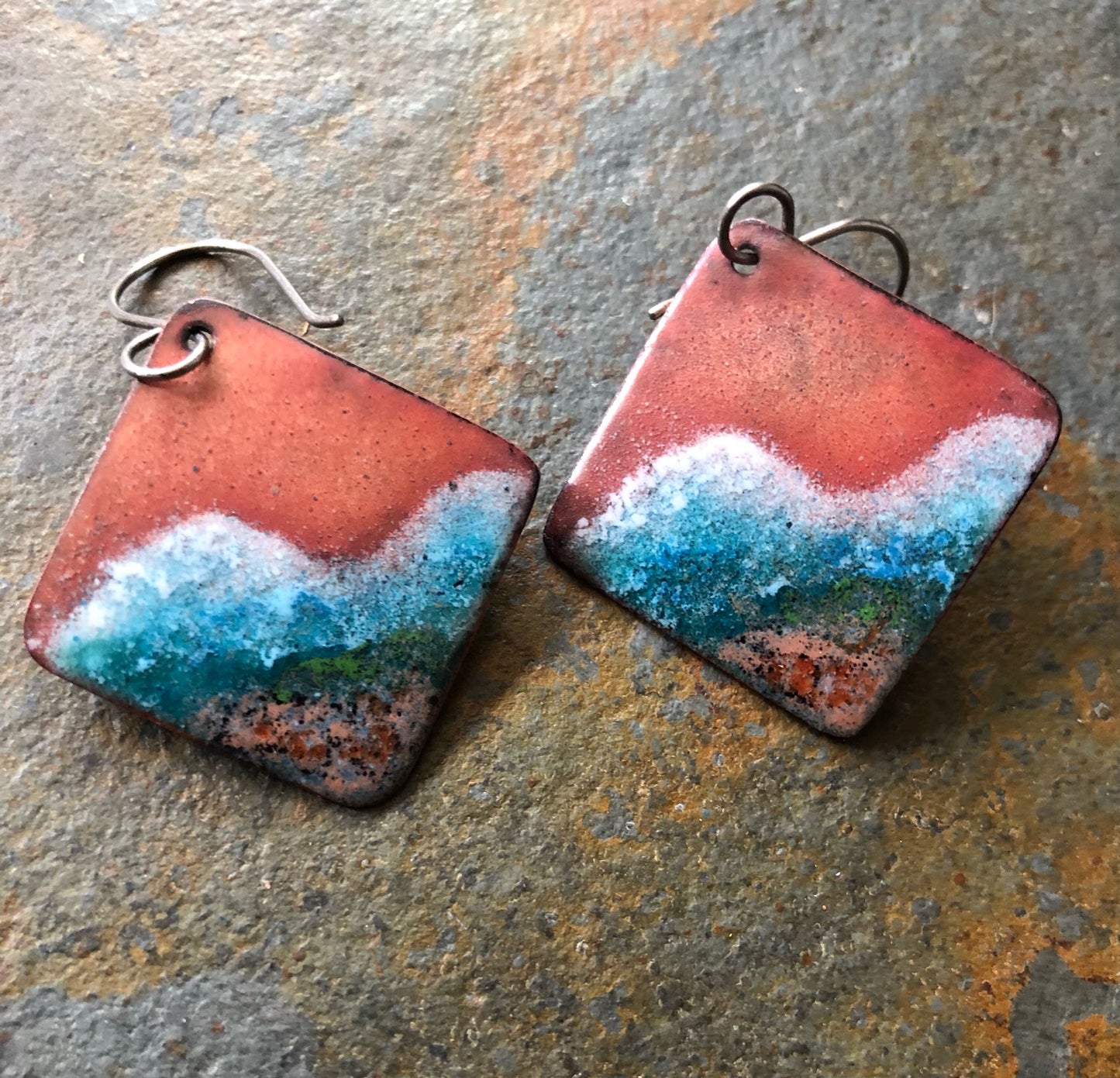 Pair of square ecopper arrings with red, blue, and white ocean gradient on a stone surface