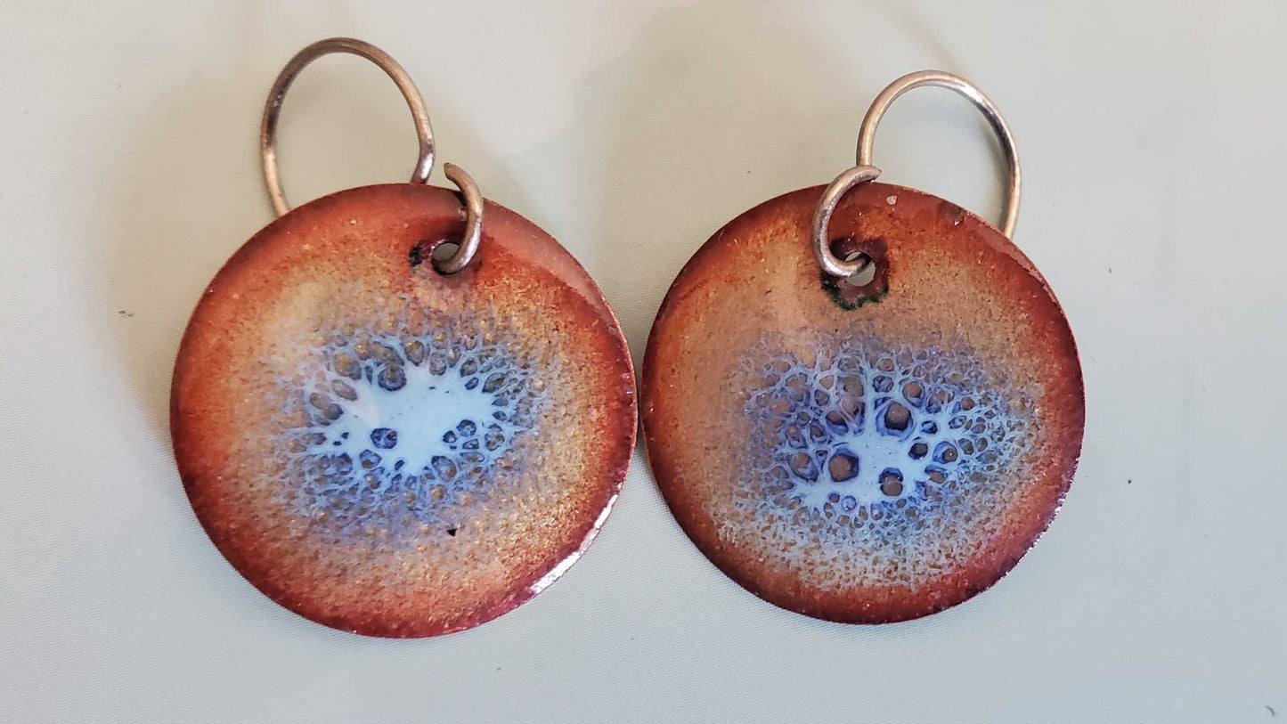 Pair of round copper earrings with a speckled design on a white background