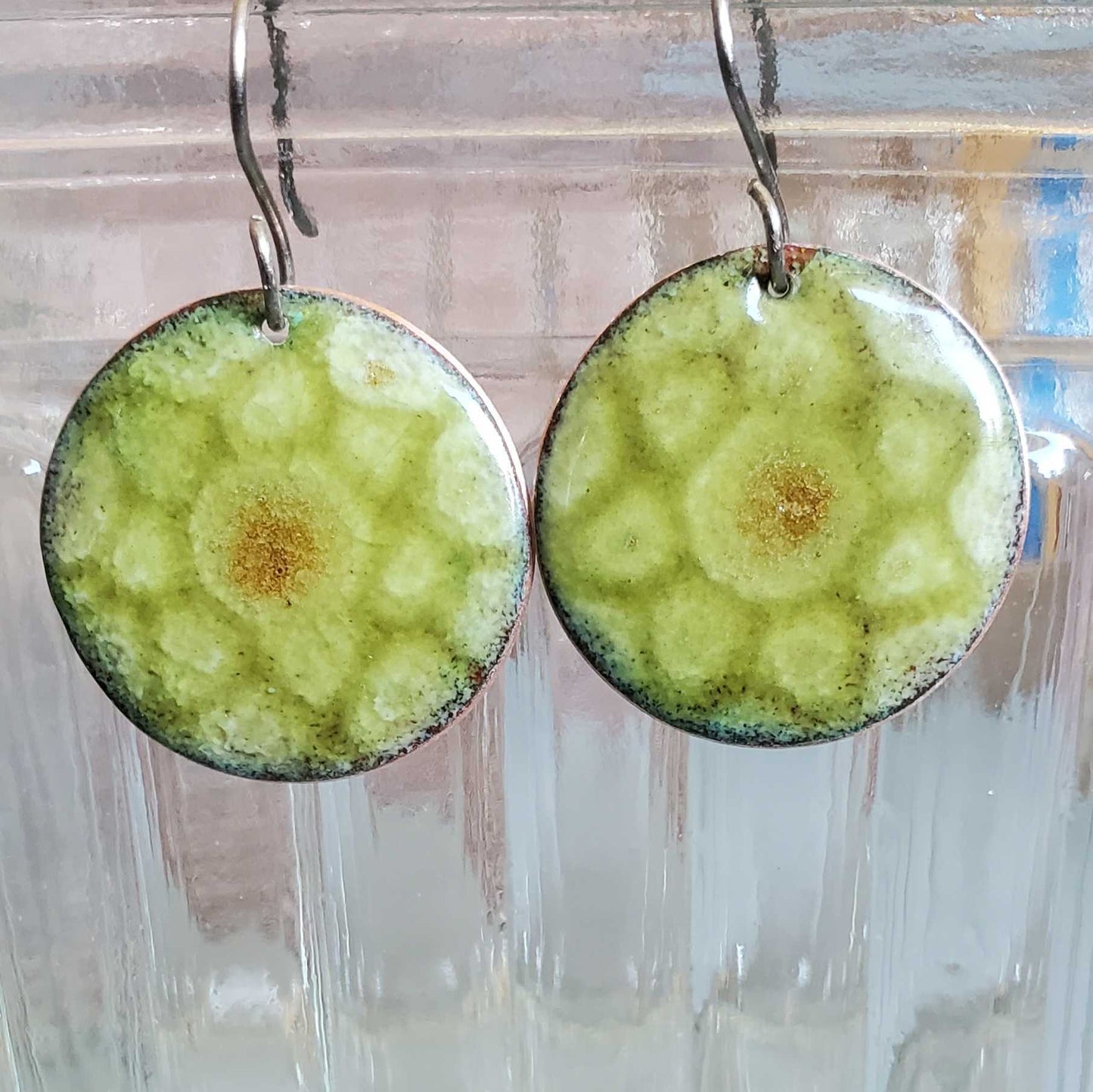 Round green copper earrings with a textured surface on a clear background