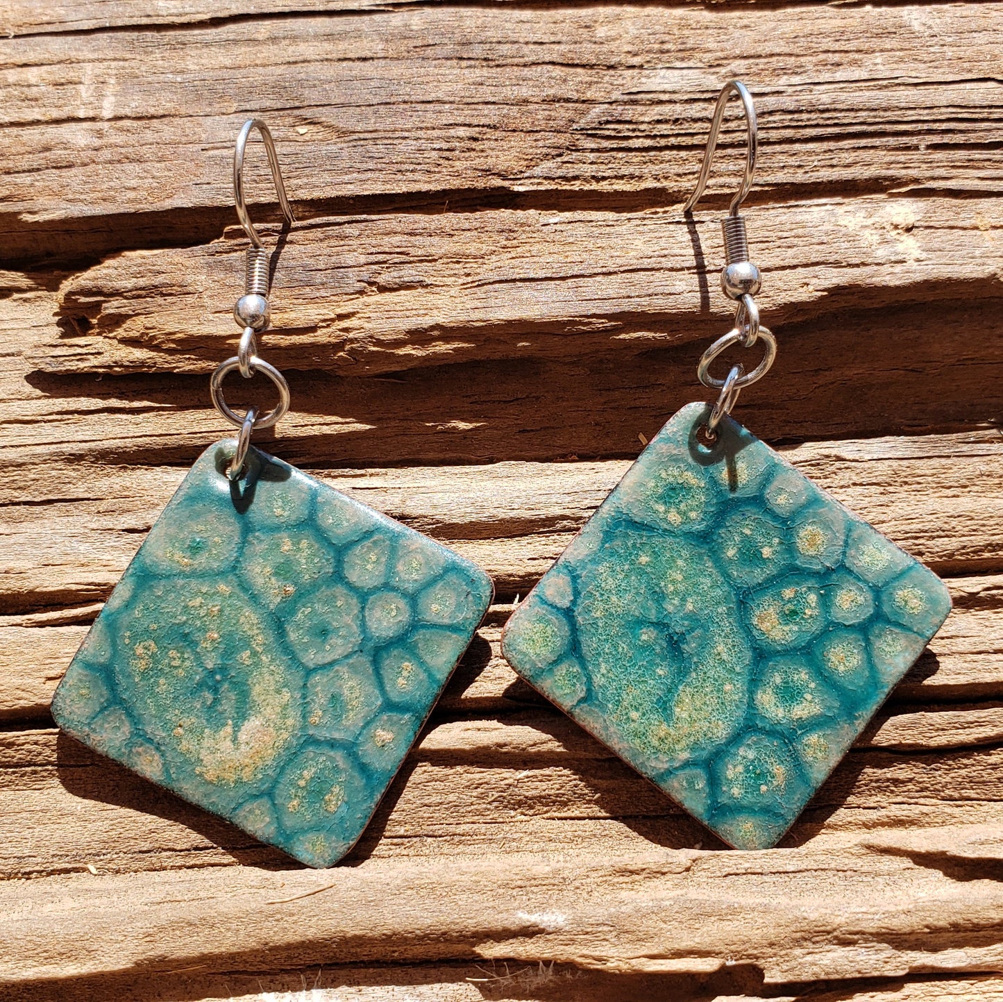 Teal copper earrings on a wooden surface