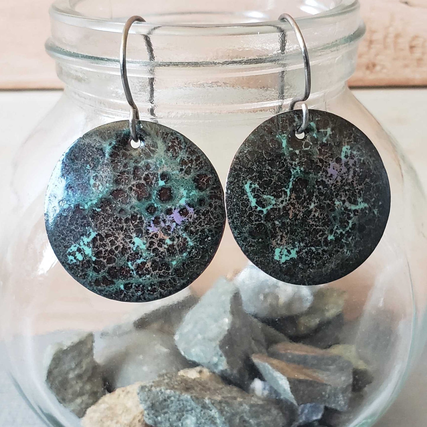 Round copper earrings with a shiny finish in a glass jar