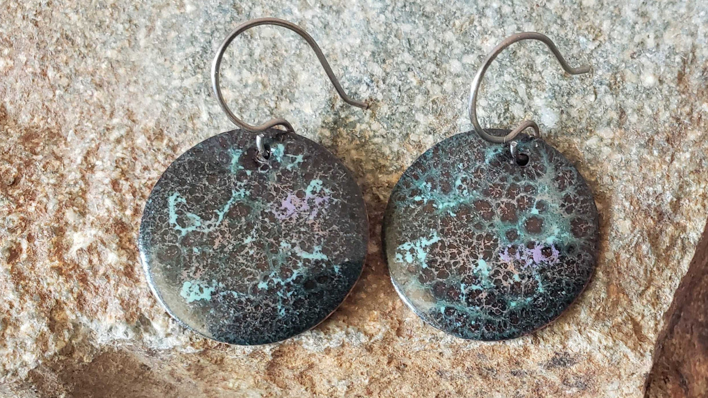 Pair of copper earrings on a stone surface