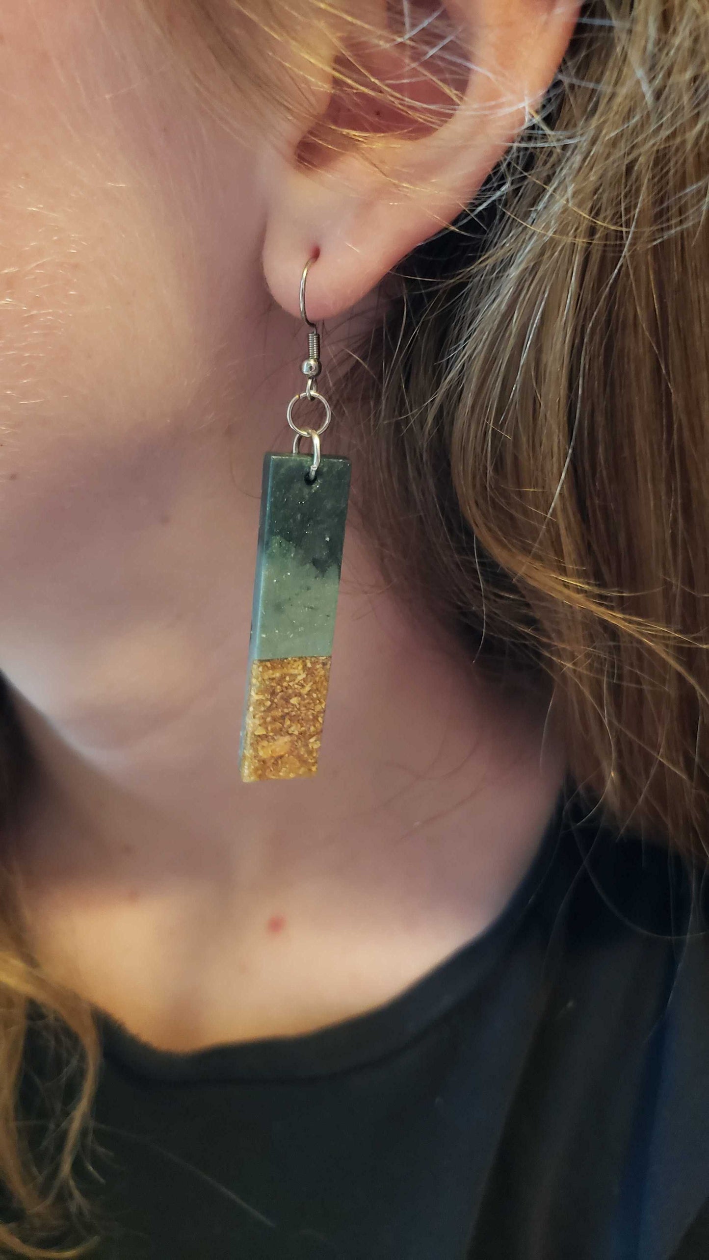 Boho dangle earring with green and gold rectangular design worn by a person