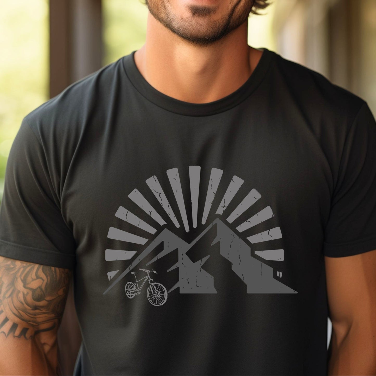 Man wearing a black t-shirt with a mountain and bike graphic and sunrise or sunset background