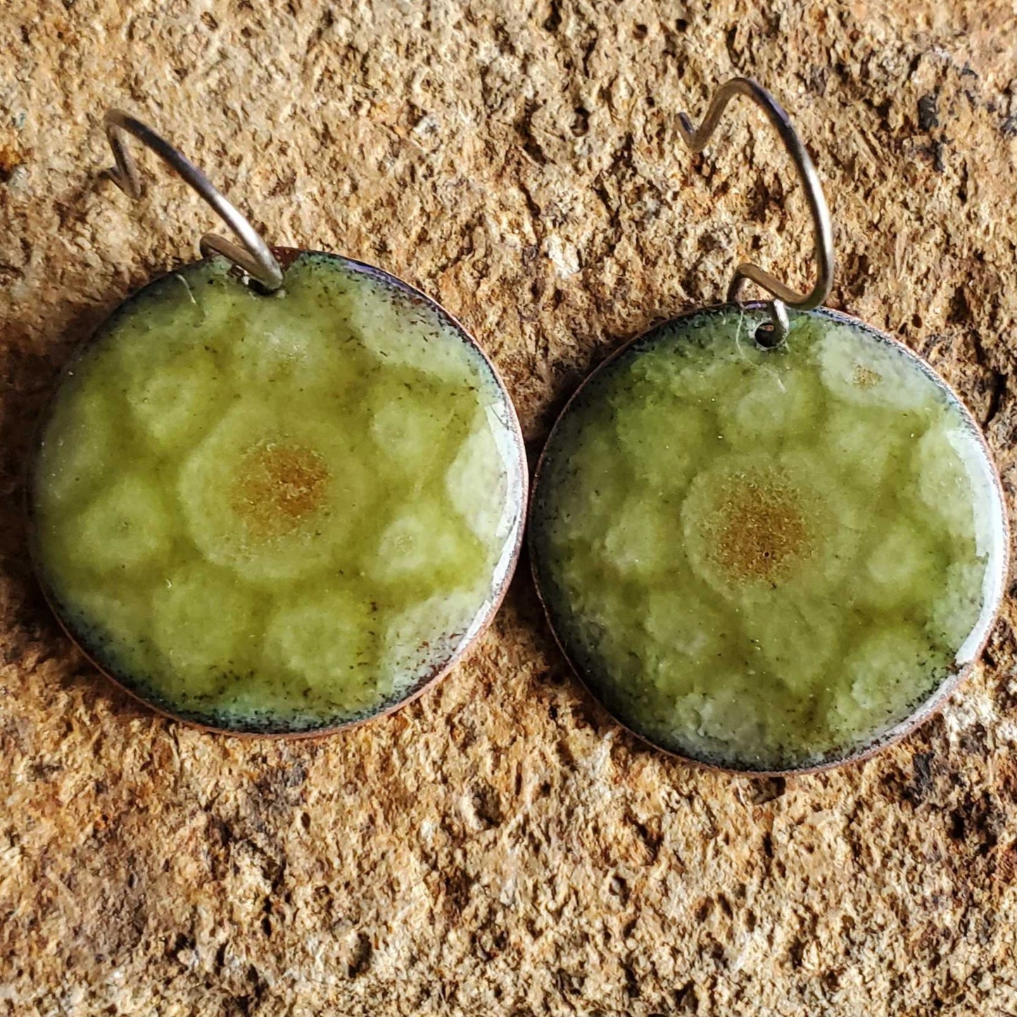 Green copper enamel earrings on a textured stone surface