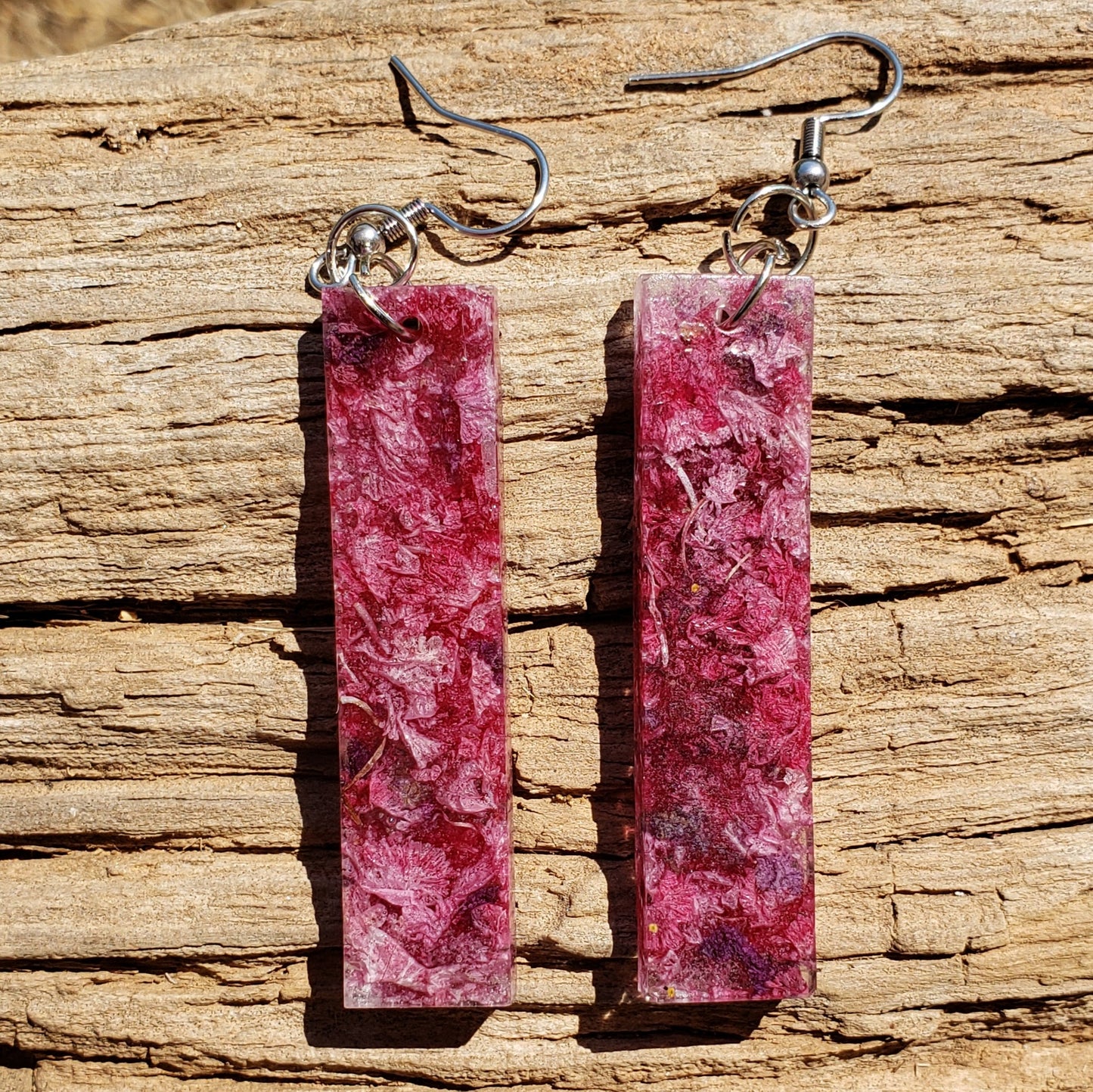 Pink long dangle rectangular earrings on a wooden surface