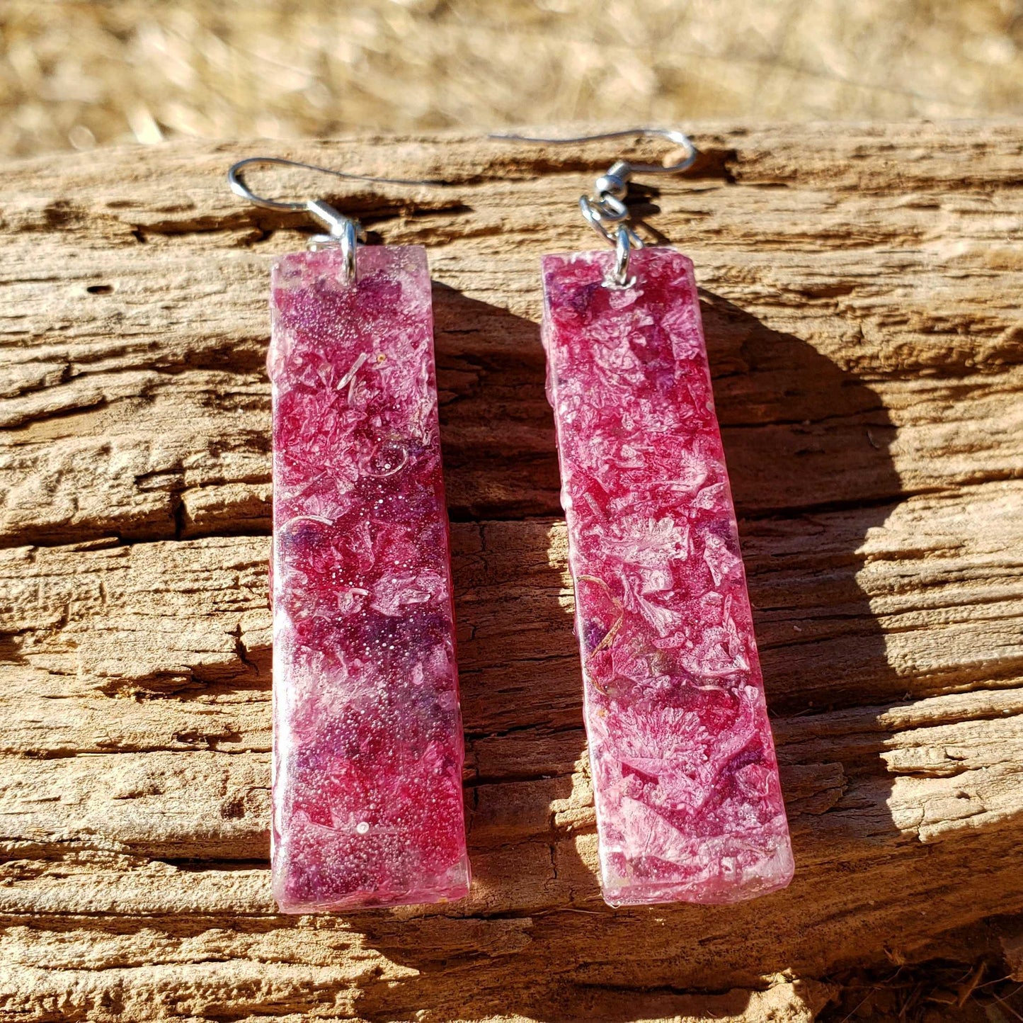 Pink long dangle rectangular earrings on a wooden surface