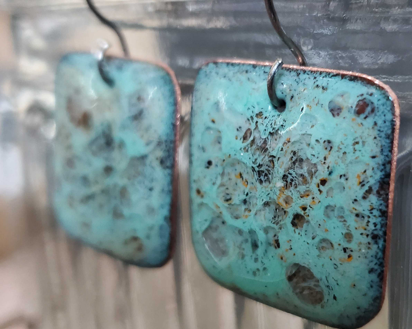 Turquoise copper earrings with a textured surface on a blurred background