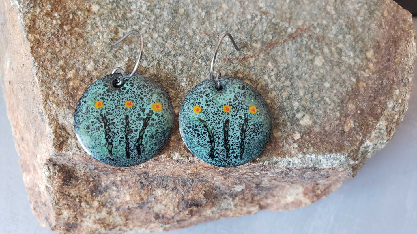 Pair of green copper turquoise speckled earrings on a stone surface