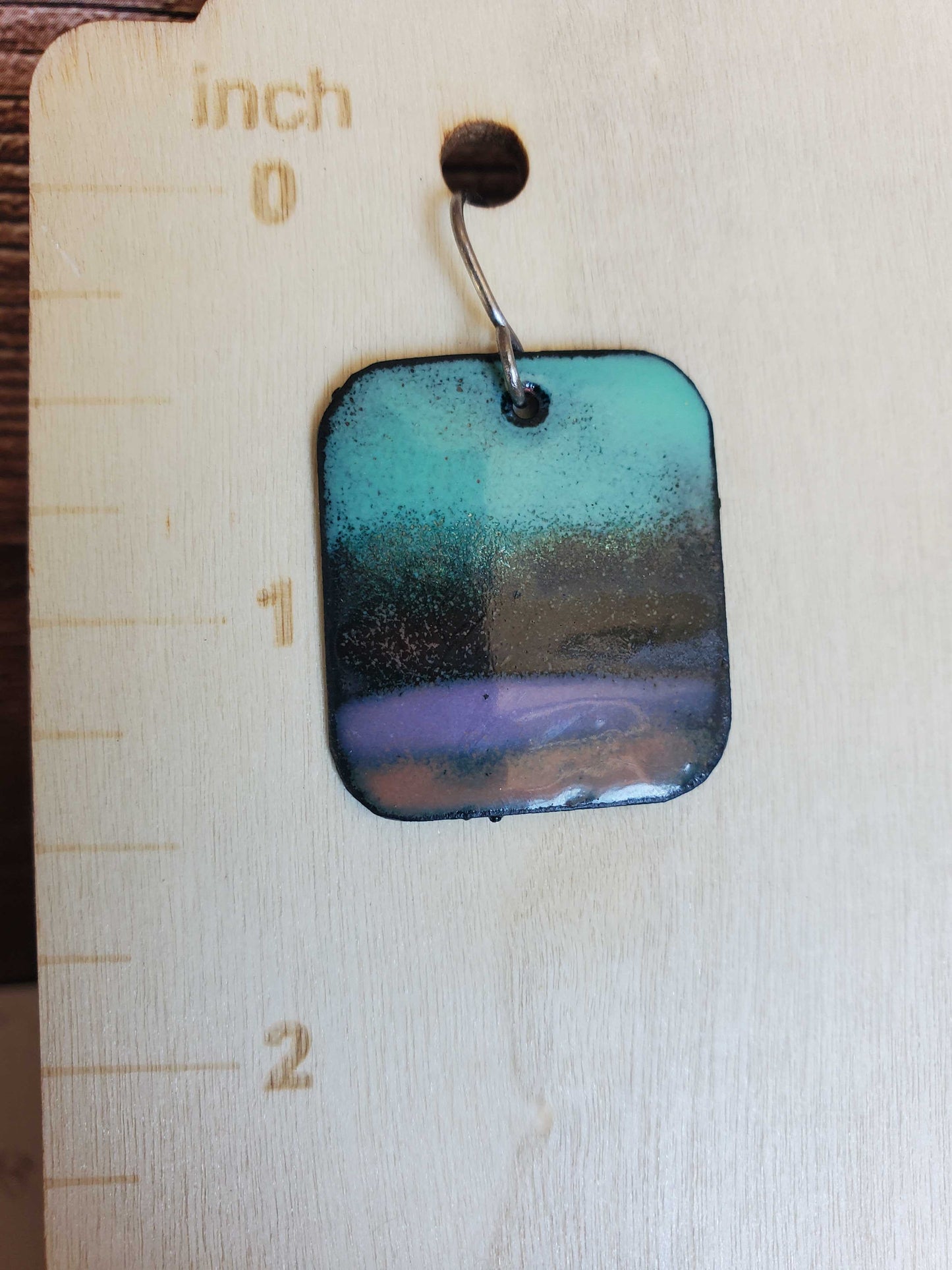 Colorful square earring on a wooden stand with measurement markings