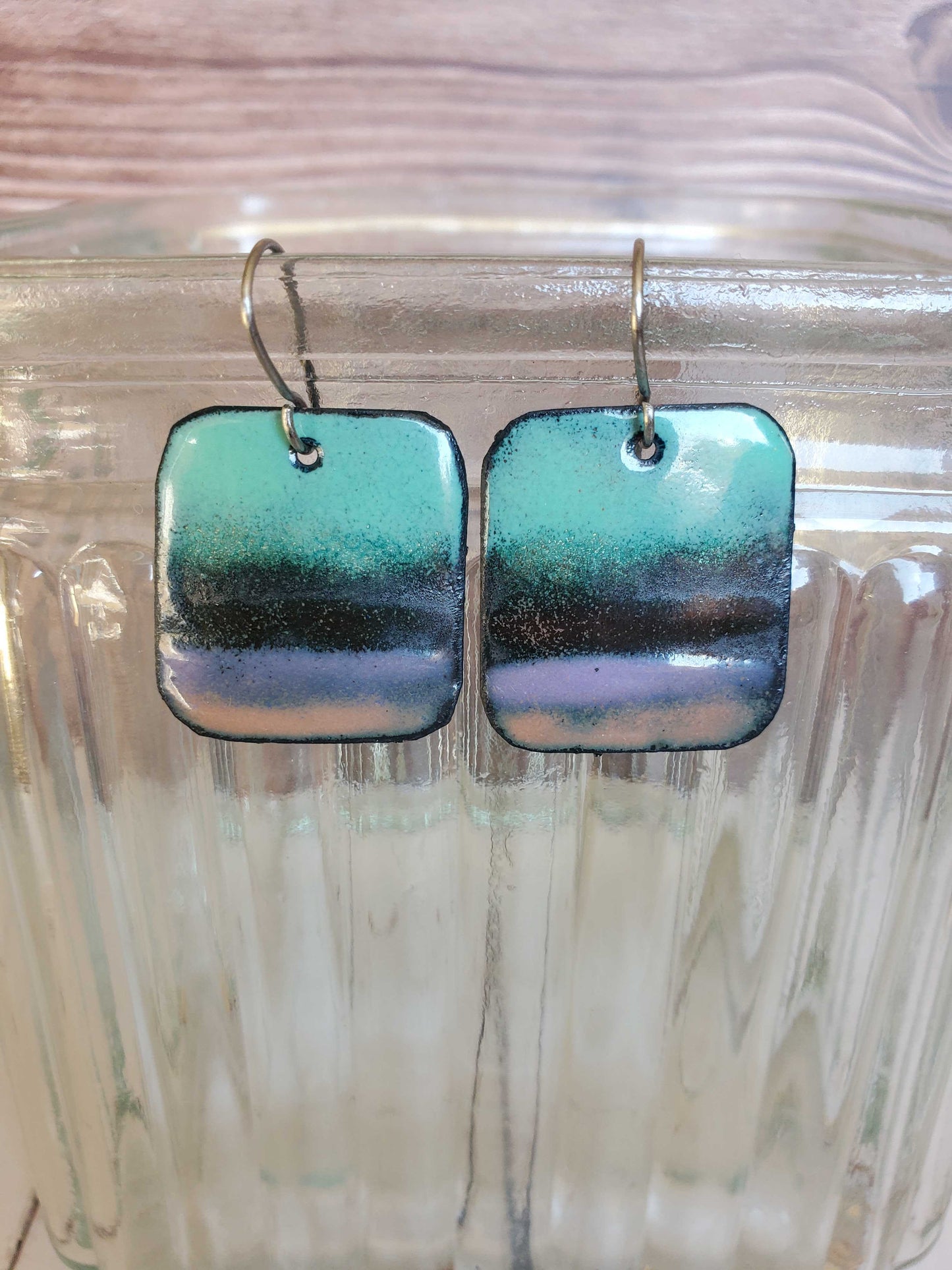 Rectangle copper earrings with a gradient design on a glass surface