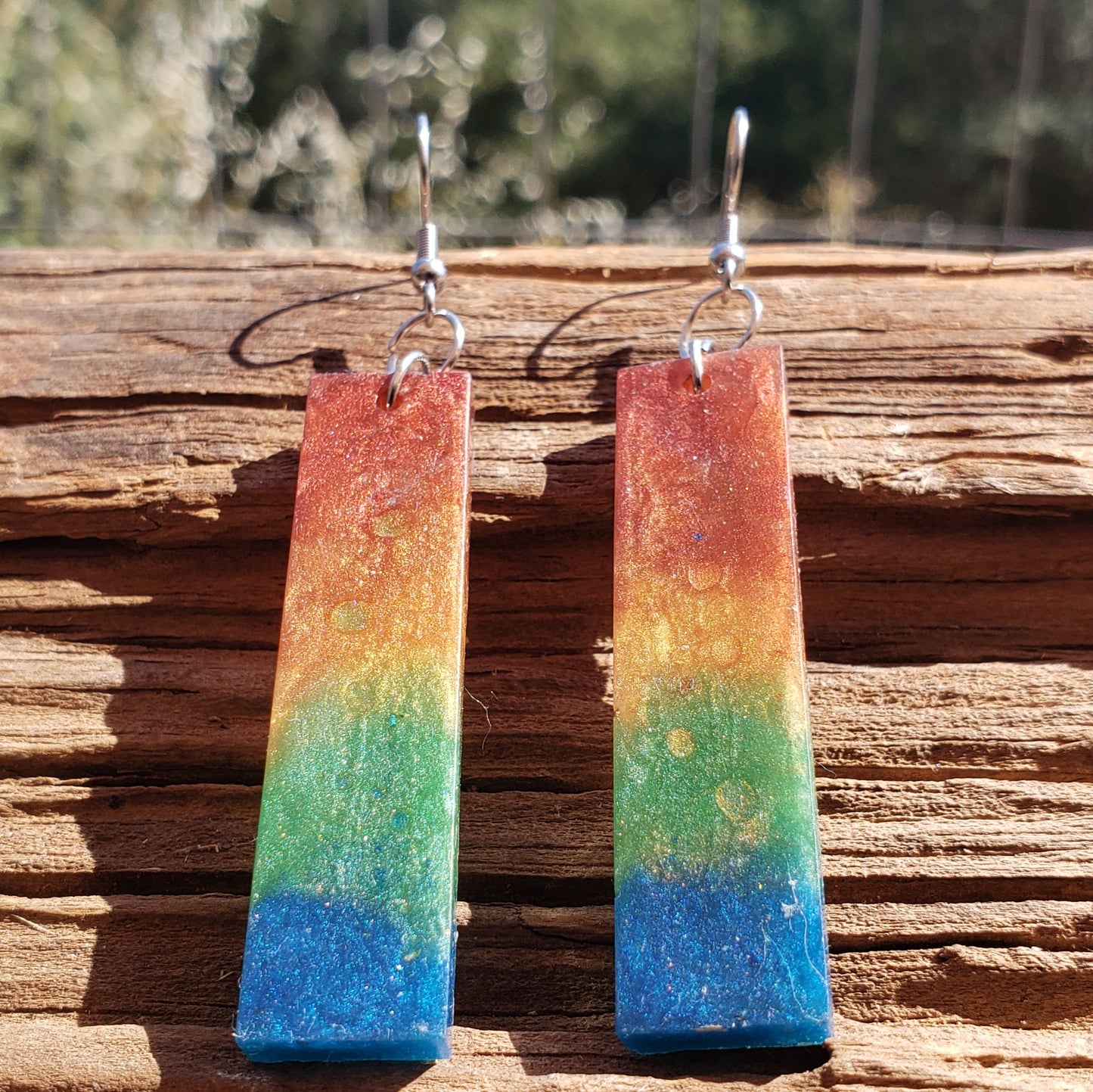 rainbow earrings rectangular shaped on a wooden surface