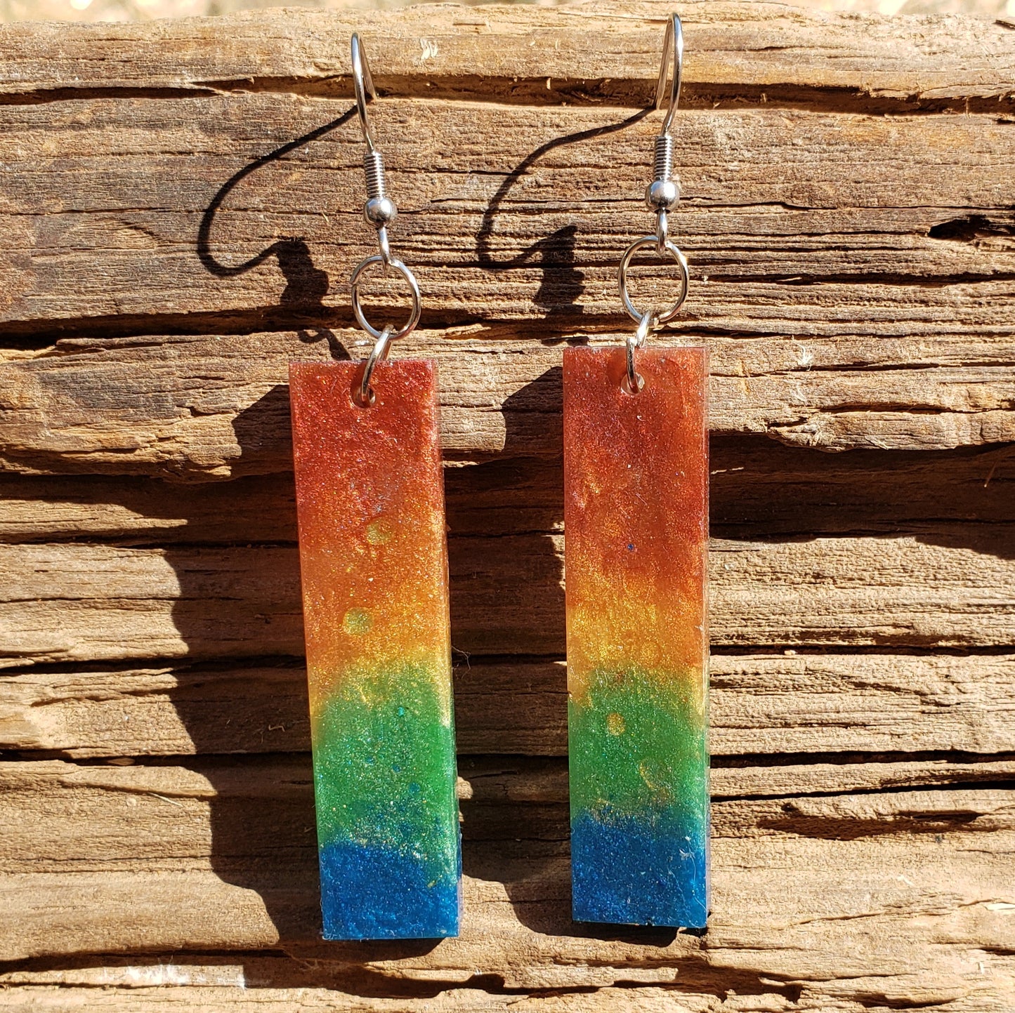 Rainbow earrings on a wooden surface