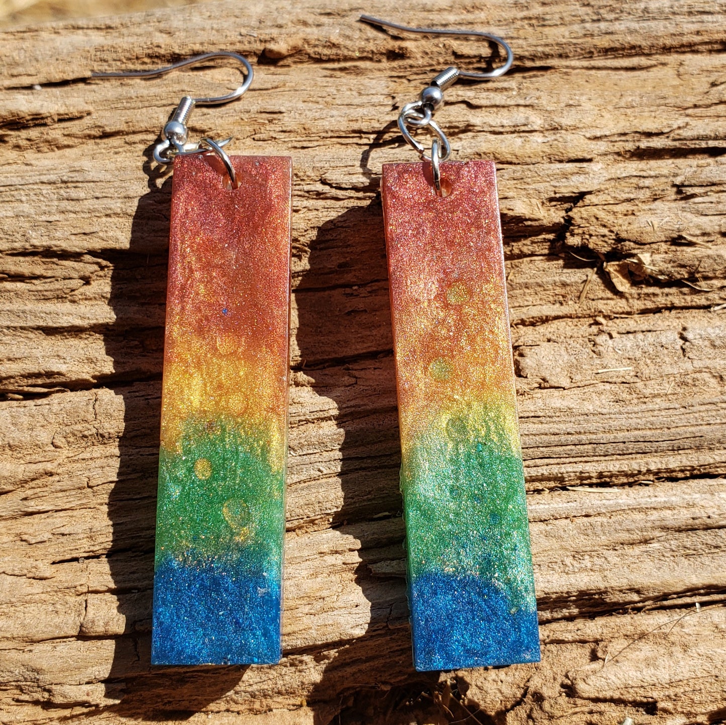Rainbow bar-shaped earrings on a wooden surface