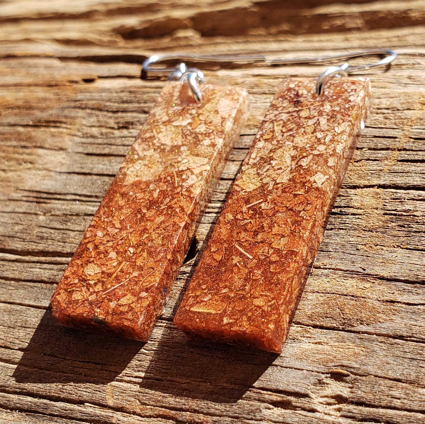 Rectangular natural brown dried leaf earrings on a wooden surface