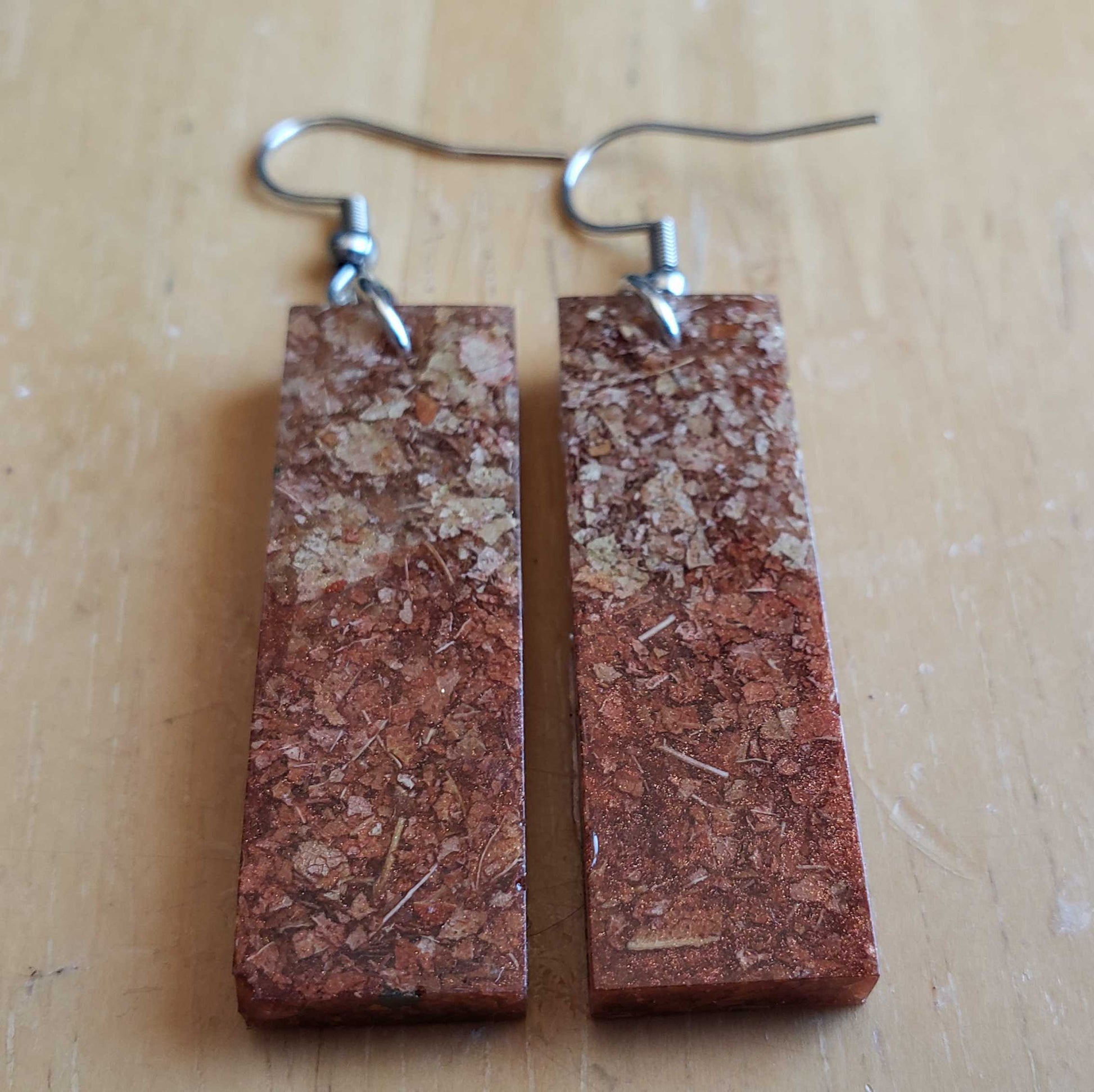 Rectangular brown dried leaf earrings on a wooden surface