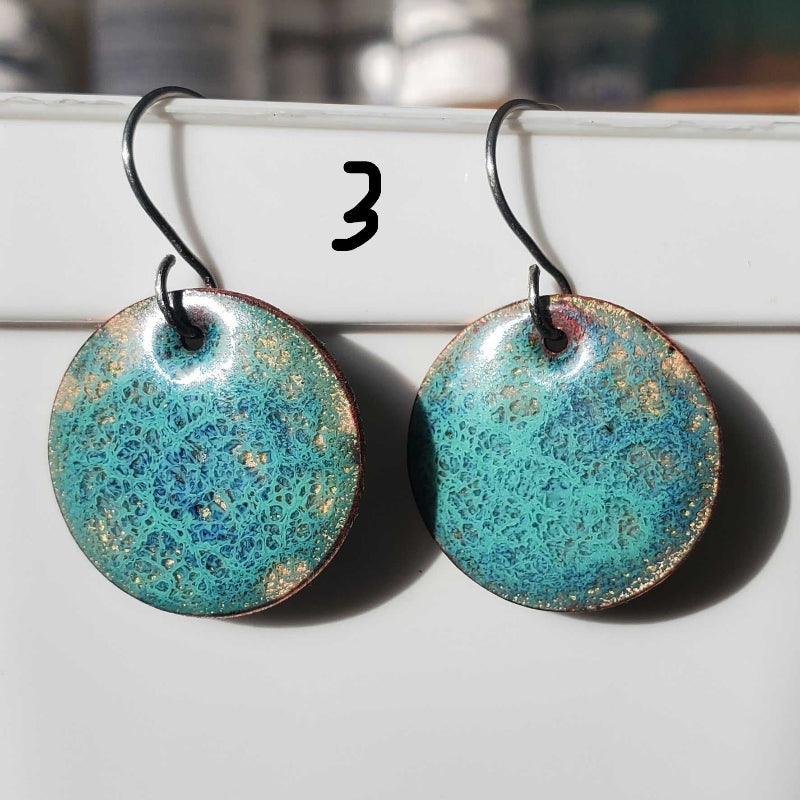Turquoise enameled copper earrings with gold speckles on a white surface