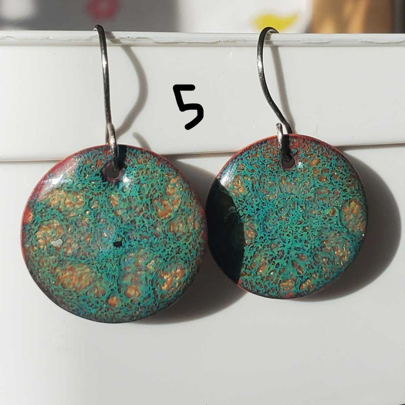Pair of round  copper earrings with textured green and brown design on a white background