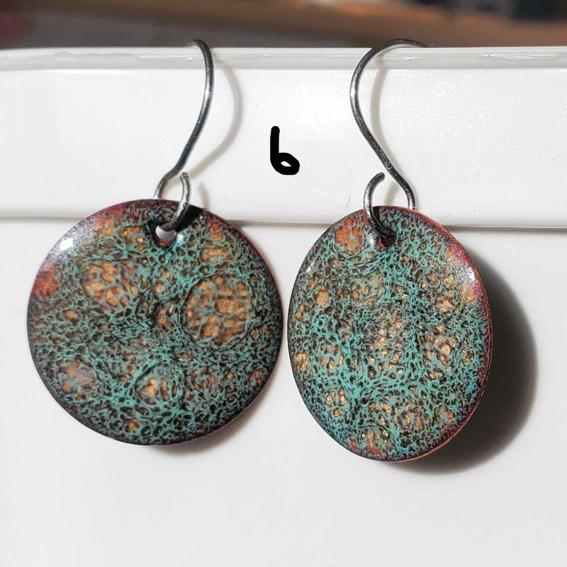 Pair of round copper earrings with textured design on a white surface