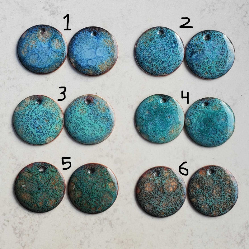 Six pairs of blue cosmic copper earrings with speckled patterns on a copper surface