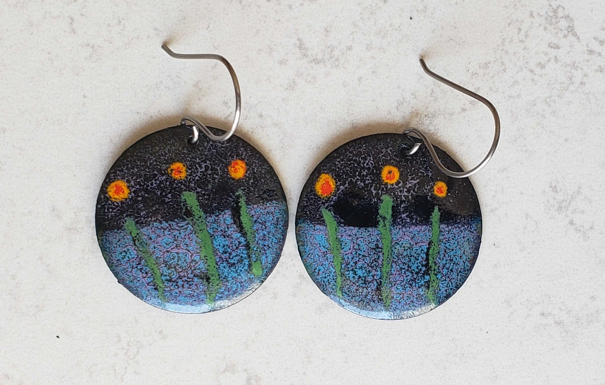 Round copper earrings with flower-themed design on a light gray background