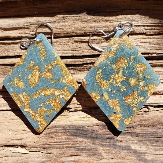 Pair of earrings with blue and gold pattern on a wooden surface