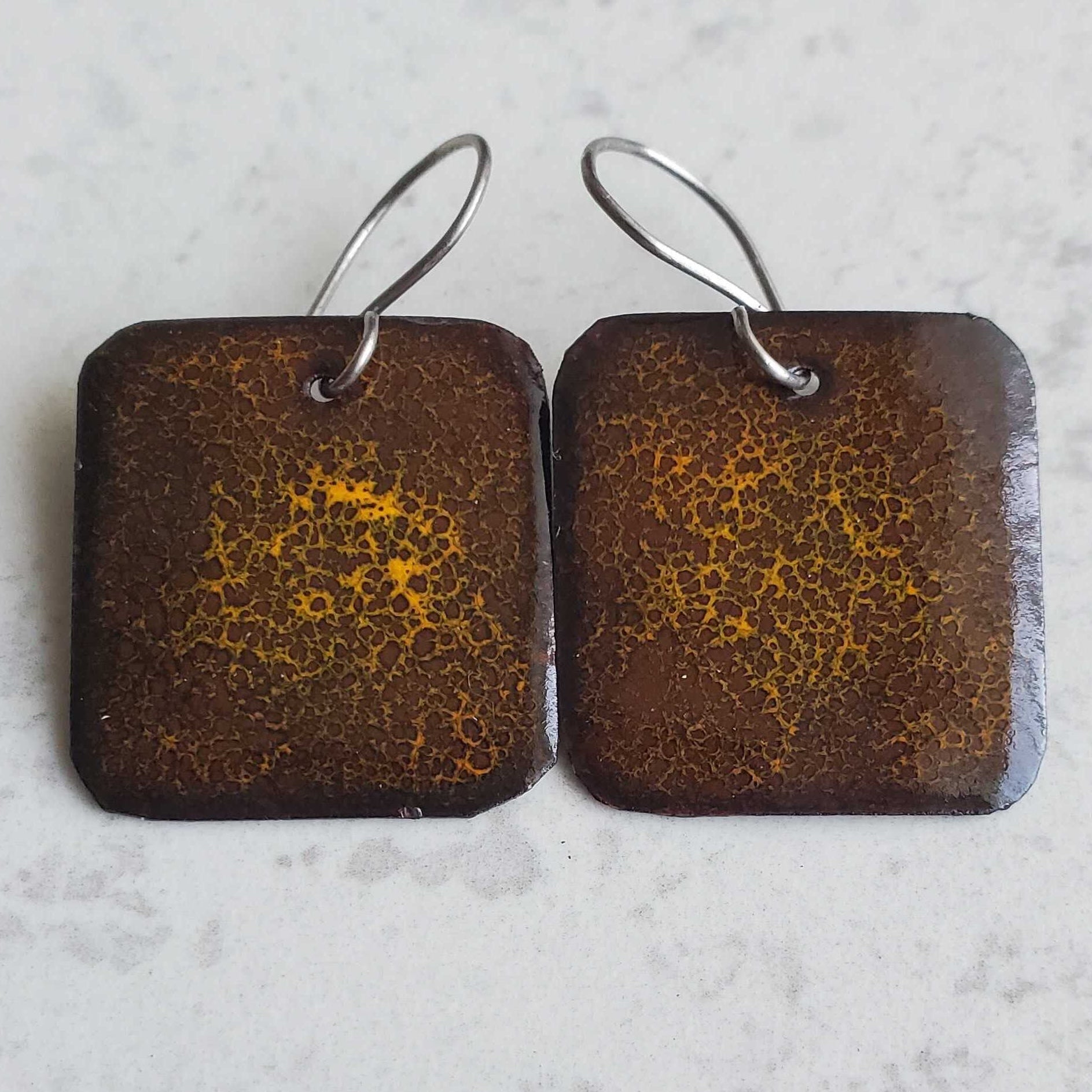 Pair of square earrings with brown and gold pattern on a light gray background