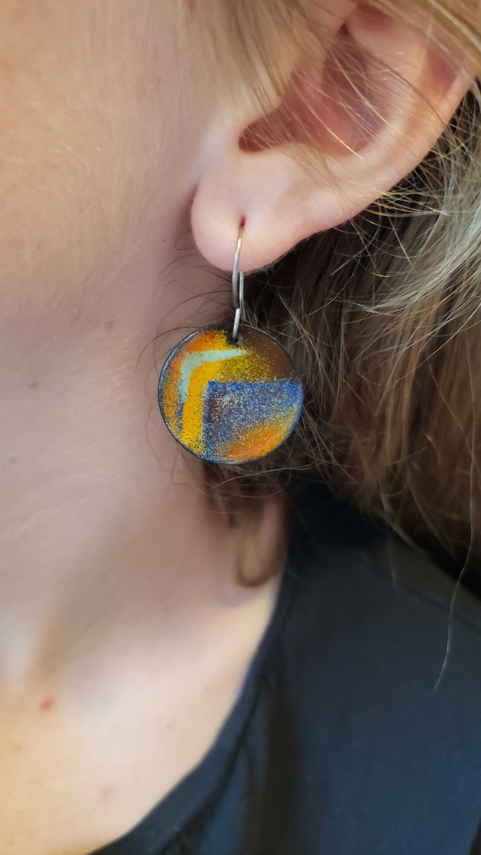 Colorful arty circle boho copper enamel earrings being worn by a person