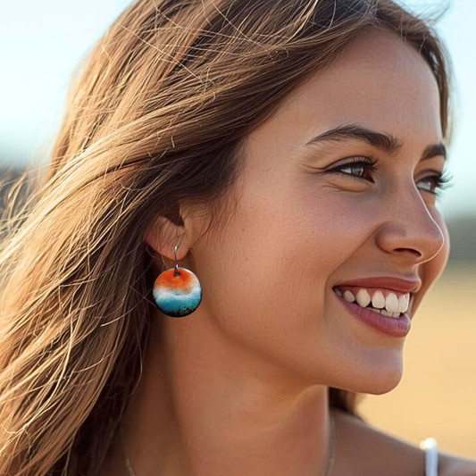 Woman wearing colorful ocean-inspired earrings with a blurred natural background