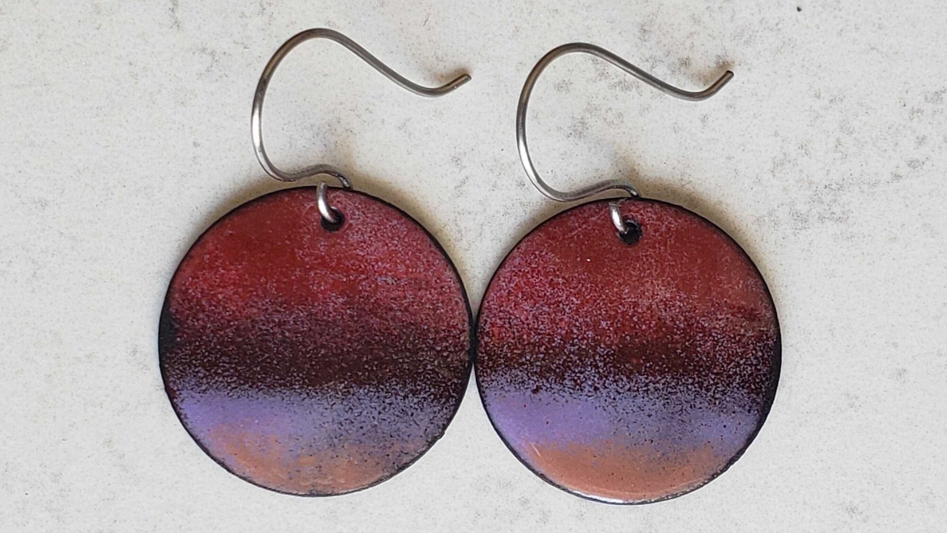 Round copper earrings with a gradient design on a light gray background