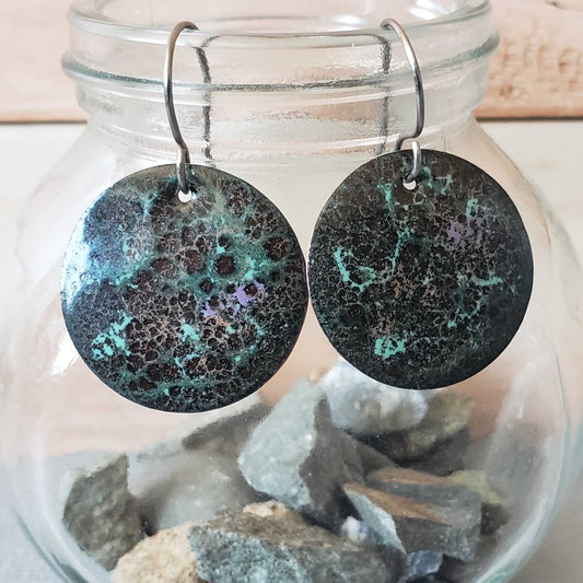 Round copper earrings with a shiny finish in a glass jar 