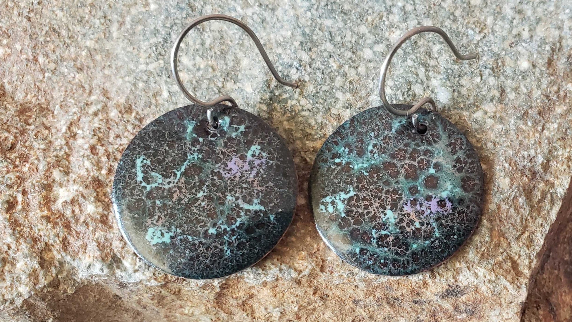 Pair of copper earrings on a stone surface