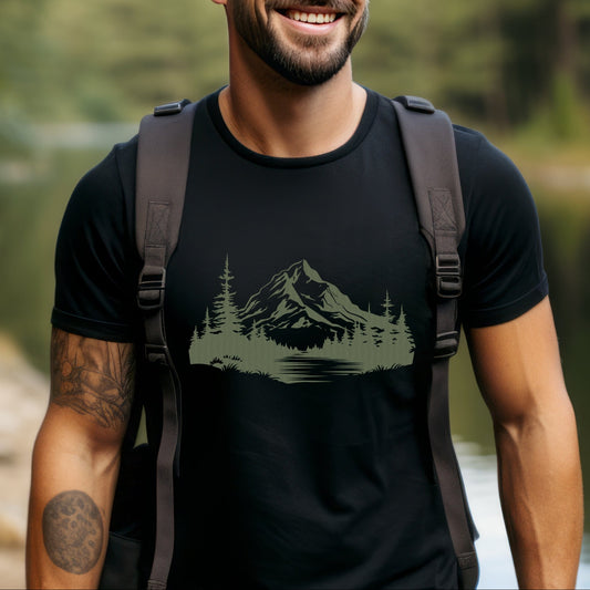 Man wearing a black t-shirt with a tree, mountain and lake design, standing outdoors.
