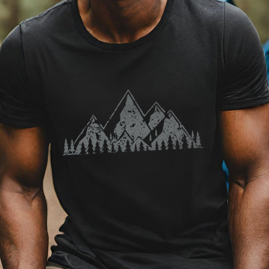 Man wearing a black t-shirt with a mountain graphic in a forest setting