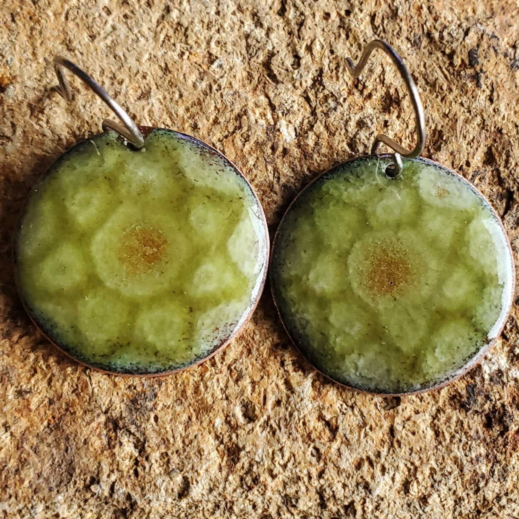 Green copper enamel earrings on a textured stone surface
