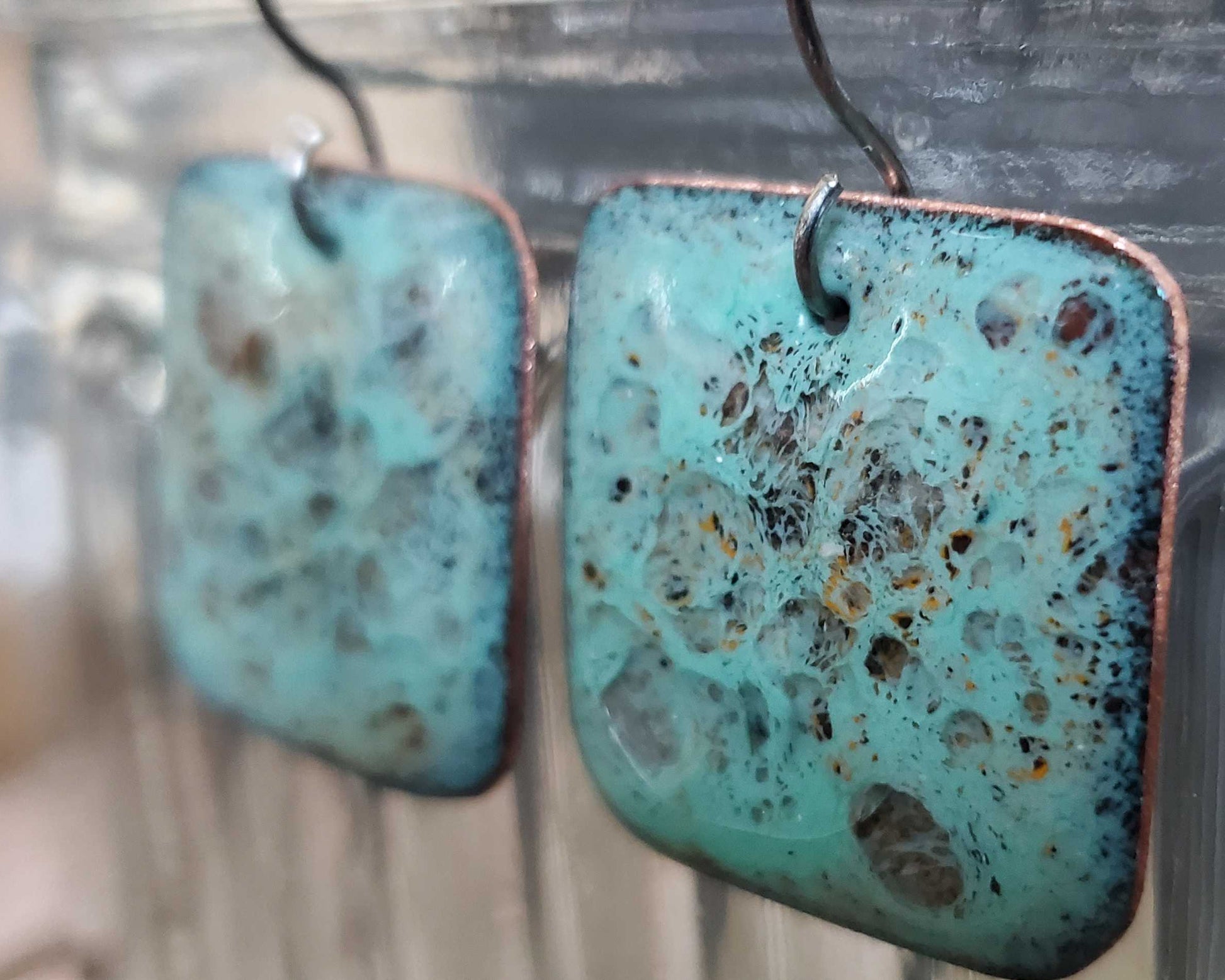 Turquoise copper earrings with a textured surface on a blurred background