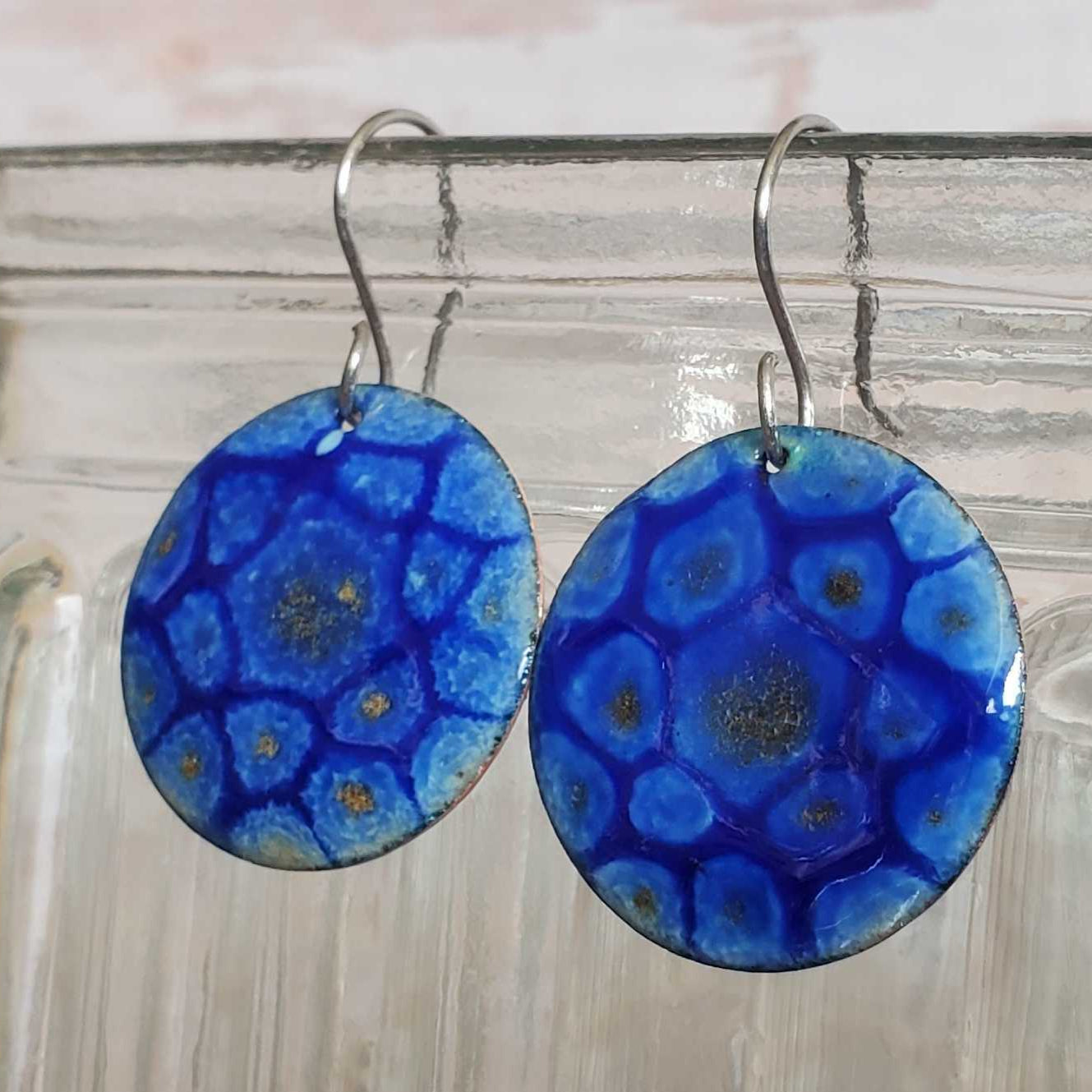 Blue copper enamel earrings hanging from a jar