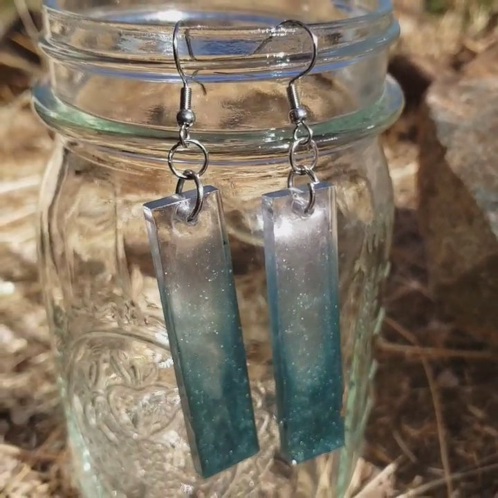Teal sparkly minimalist dangle earrings on glass